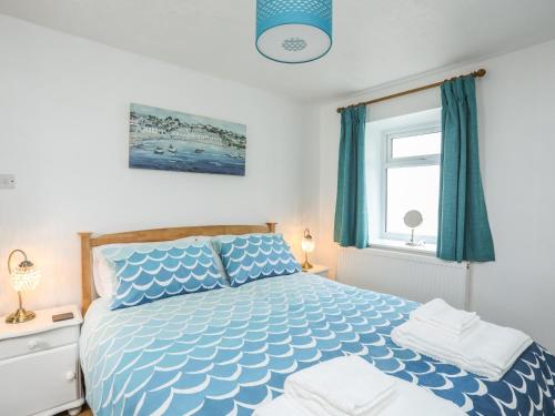 een slaapkamer met een blauw en wit bed en een raam bij Church Gate Cottage in Beaumaris