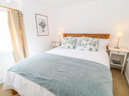 a bedroom with a bed with a blue blanket on it at Boo Cottage in Taunton