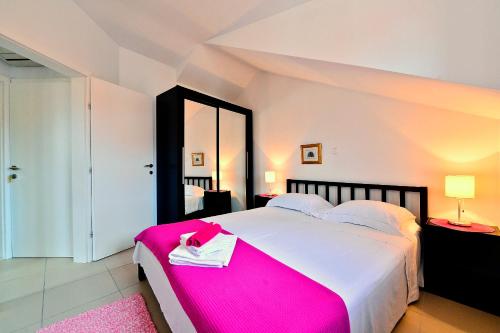 a bedroom with a large bed with a pink blanket at Sunny Bobica Apartments in Vodice