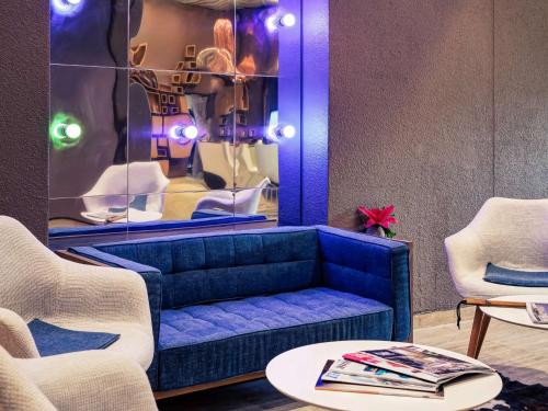 a blue couch in a room with two chairs and a table at Mercure Lyon Charbonnières in Charbonnières-les-Bains