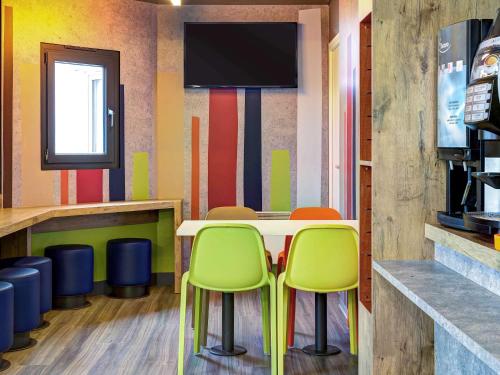 a restaurant with colorful walls and a table and chairs at ibis Budget Caen Memorial in Caen