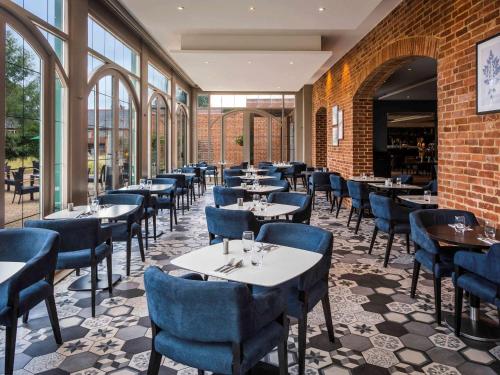 Un restaurante con mesas, sillas y ventanas. en Walton Hall Hotel & Spa by Sunday, en Wellesbourne