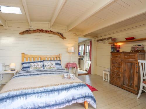 a bedroom with a bed and a wooden floor at Songbird Hideaway in Pwllheli