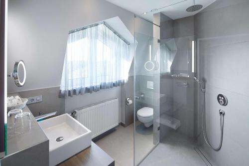 a bathroom with a shower and a toilet and a sink at Best Western Plus Arosa Hotel in Paderborn