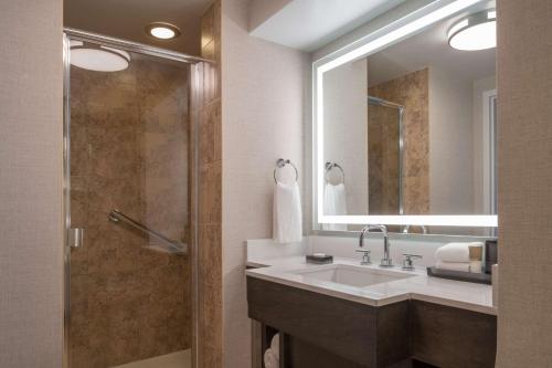 
a bathroom with a shower, sink, and mirror at Hyatt Regency Orlando International Airport Hotel in Orlando
