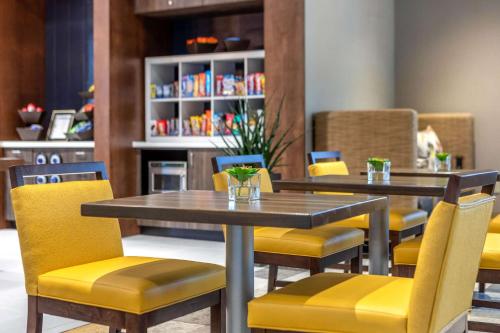 a dining room with two tables and yellow chairs at Cambria Hotel Milwaukee Downtown in Milwaukee