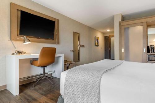 a bedroom with a bed and a desk with a television at Cambria Hotel Milwaukee Downtown in Milwaukee