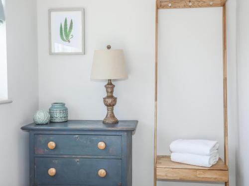 Un espejo junto a un tocador azul con una lámpara. en Southcott Apartment, en Trearddur