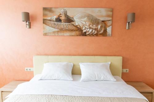 a bedroom with a bed with a painting on the wall at Audros Apartamentai in Kaunas