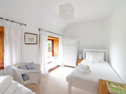 a white bedroom with a bed and a chair at Cardean Mill in Blairgowrie