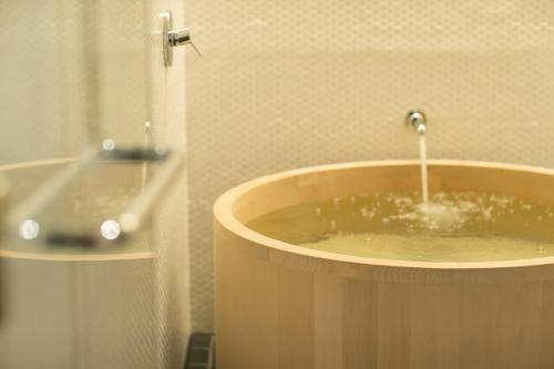 a bath tub with a faucet in a bathroom at hotel kanra kyoto in Kyoto