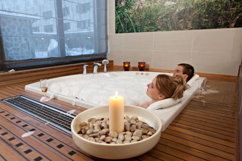 a man and woman laying in a bath tub with a candle at Rokua Health & Spa in Rokua