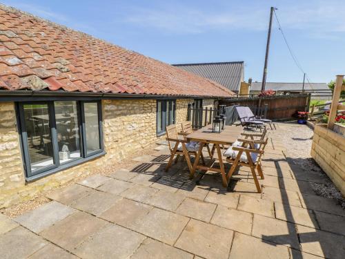 a patio with a wooden table and chairs on it at Puddleducks in Sherborne