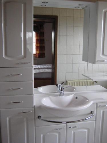 a white bathroom with a sink and a mirror at Ferienwohnungen Haberberger in Pottenstein