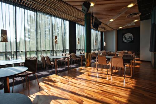 Rokua Health & Spa في Rokua: مطعم بطاولات وكراسي ونوافذ كبيرة