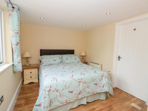 um quarto com uma cama com colcha floral em Eastdown Annexe em Totnes