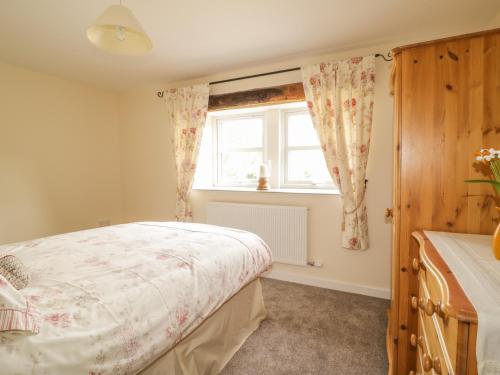 a bedroom with a bed and a window at The Barn in Workington