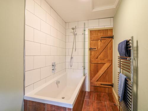 een badkamer met een ligbad en een houten deur bij Heather Cottage in Penzance