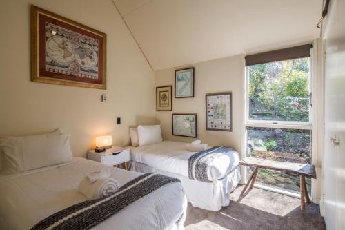 two beds in a small room with a window at Panoramic: farmhouse theme with shared spa pool in Queenstown