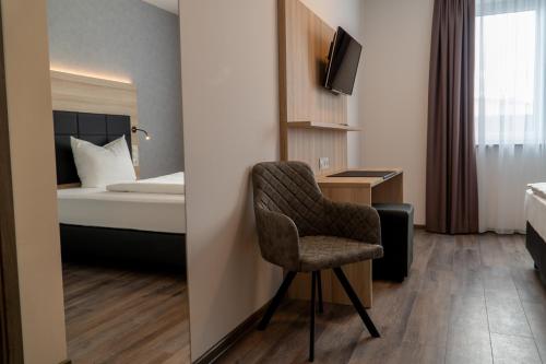 een hotelkamer met een stoel en een bed bij Hotel Schlafplatz in Rodgau