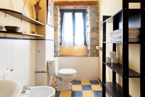 baño con aseo y lavabo y ventana en Casas Arana - Parque Nacional De Ordesa, en Albella