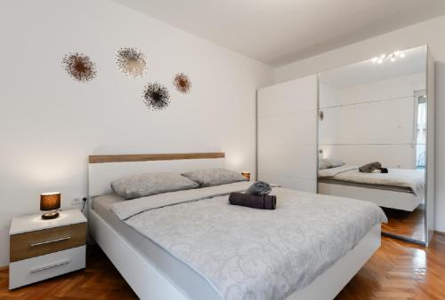 a white bedroom with a large bed and a mirror at Donatus - Modern apartment near the bridge/centre in Zadar