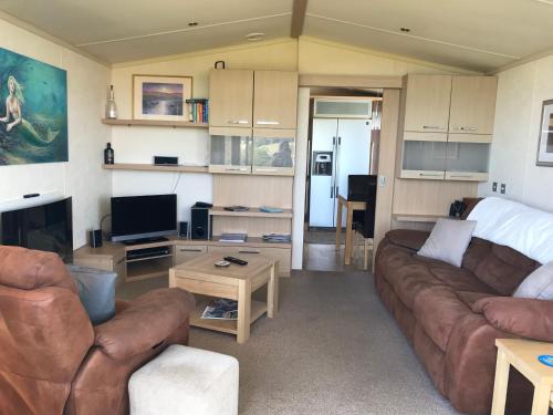 ein Wohnzimmer mit einem Sofa und einem TV in der Unterkunft Blue Water Breaks - Dawlish Warren in Dawlish
