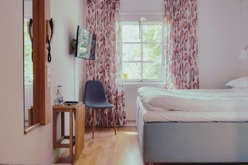 1 dormitorio con 1 cama, 1 silla y 1 ventana en Balingsholm, en Huddinge