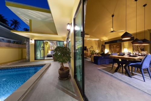 a house with a swimming pool and a dining room at Baan Putahracsa in Laem Sor