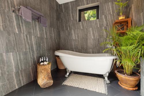 a bathroom with a white bath tub and plants at Baan Putahracsa in Laem Sor