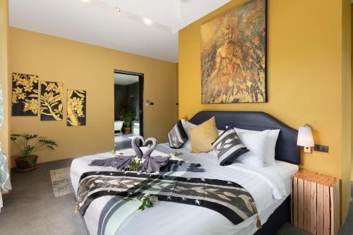 a bedroom with a large bed and a painting on the wall at Baan Putahracsa in Laem Sor