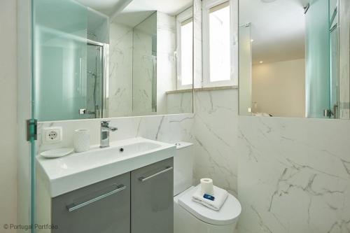ein Badezimmer mit einem Waschbecken, einem WC und einem Spiegel in der Unterkunft Bica Apartment in Lissabon