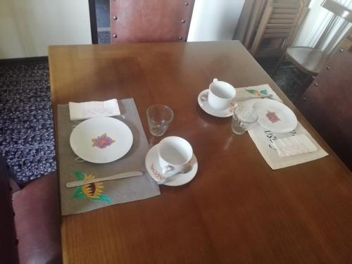 a wooden table with two cups and plates on it at Casa vacanze da Medardo in Gagliano Aterno