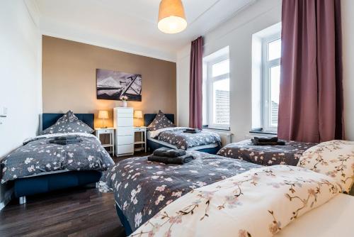a bedroom with two beds and a desk and two windows at Adora Apartment Hilden in Hilden