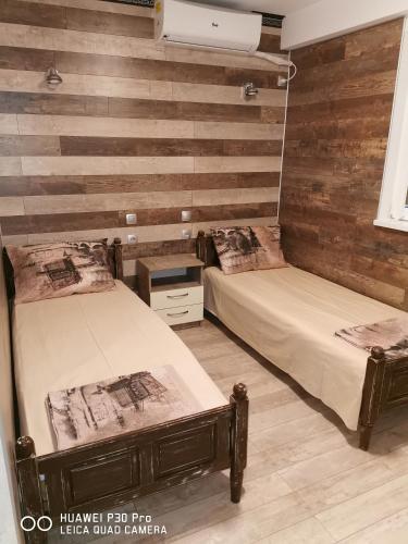two beds in a room with wooden walls at Hotel Belisimo in Ruse