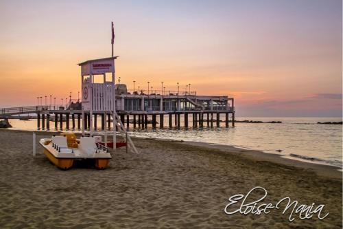 een pier op het strand met een boot op het zand bij Hotel Resort Marinella in Gabicce Mare