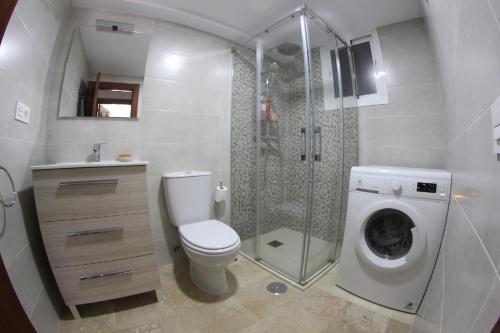 ein Badezimmer mit einer Dusche, einem WC und einer Waschmaschine in der Unterkunft Playa Bella 3-1E in Estepona