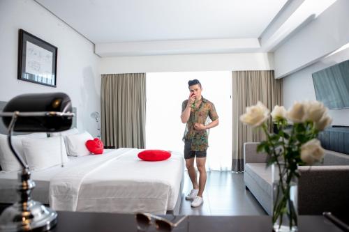 a man talking on a cell phone in a hotel room at Sugar Palm Grand Hillside - SHA Plus in Kata Beach