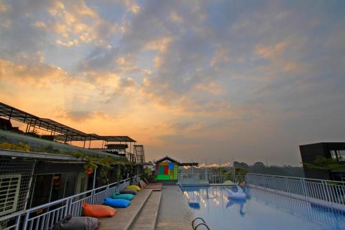 a swimming pool on top of a building with a sunset at Grand Tjokro Premiere Bandung in Bandung