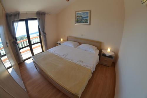 a bedroom with a bed with two lamps and a balcony at Apartman Jadranka in Rab