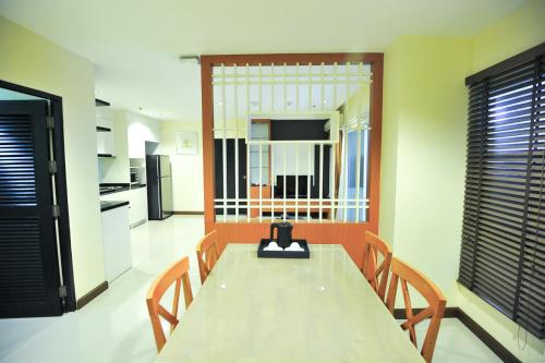 a dining room with a table and chairs and a kitchen at 42Grand Residence in Bangkok