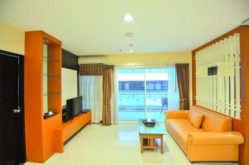 a living room with an orange couch and a television at 42Grand Residence in Bangkok