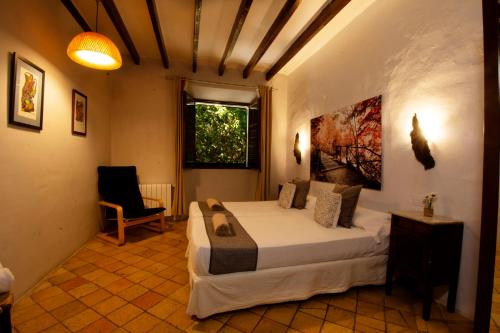 a bedroom with a bed and a chair and a window at S´Hostal d´Esporles in Esporles