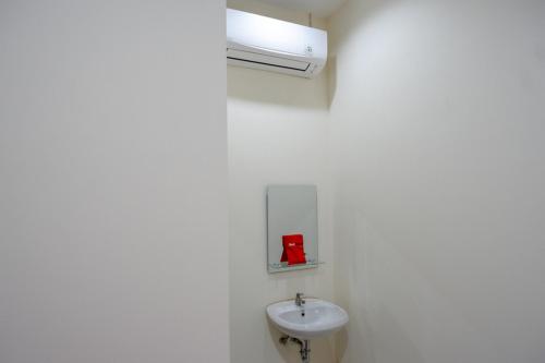 RedDoorz near Living Plaza Purwokerto في بوروكيرتو: حمام مع حوض و جدار أبيض