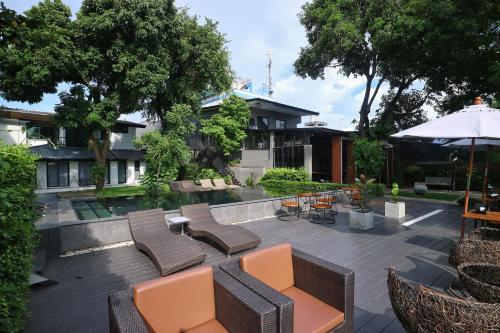 eine Terrasse mit Stühlen, Tischen und einem Sonnenschirm in der Unterkunft i-river chiangmai in Chiang Mai