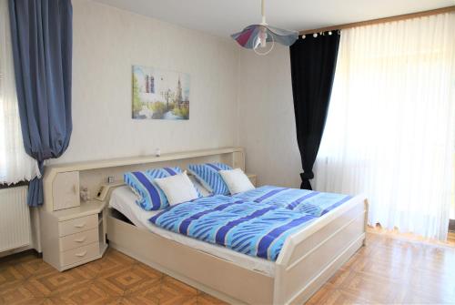 um quarto com uma cama com lençóis azuis e brancos em Ferienwohnung Röhrer em Obertrubach