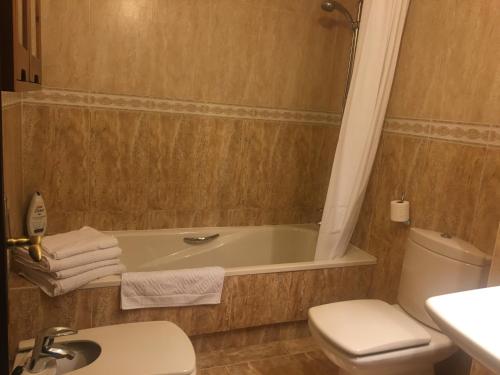 ein Badezimmer mit einer Badewanne, einem WC und einem Waschbecken in der Unterkunft Apartamentos Confortarte in Oviedo