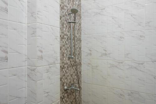 a bathroom with a shower with white tiles at RedDoorz Plus @ Hotel Sempurna Watervang Lubuk Linggau in Lubuklinggau