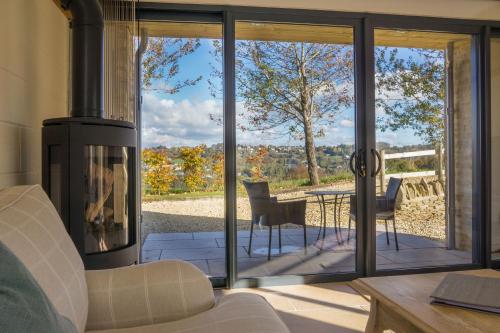 a living room with a fireplace and a patio at Vineyard Barn Room in Woodchester