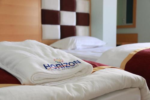 a pile of towels sitting on top of two beds at Horizon Hotel Apartments - الأفق للشقق الفندقية in Al Khawḑ